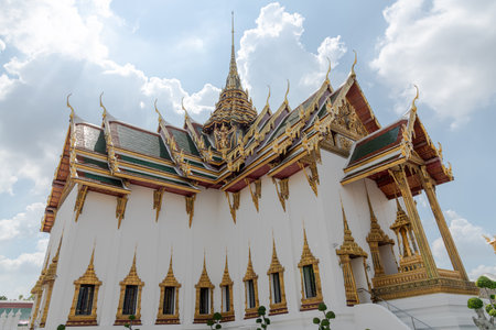 A magnificent ornate Thai temple features a stunning golden roof set against a vibrant blue sky, Bangkok, Thailandの写真素材