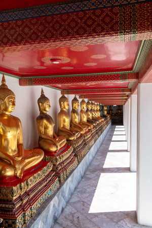 The Serene and Peaceful Buddhist Temple Corridor Adorned with Beautiful Golden Statuesの写真素材