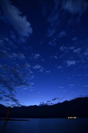 An early morning sky with the sky, cloud and the stars above the mountain and lakeの写真素材