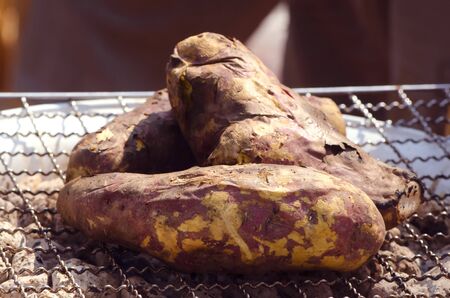 A sweet potato on a gridiron grill by charcoal with the sunlight in a organic food marketの写真素材