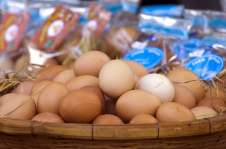 An organic chicken's eggs on a bamboo basket in an organic market cover with a bit of straw and blur...