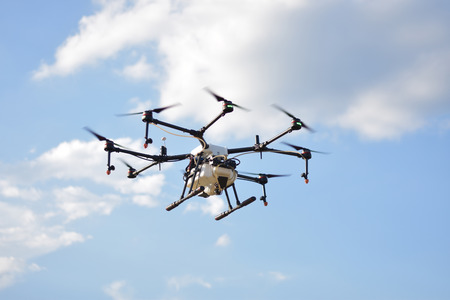 Flying agriculture drone, photo image of agriculture drone carry a tank of liquid fertilizer