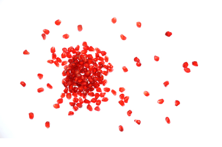 Isolated pomegranate seeds, top view closeup image of scattered pomegranate seeds isolated on white background, red seeds of pomegranate after peeled, tropical fruit healthy food, red fruit grainの写真素材