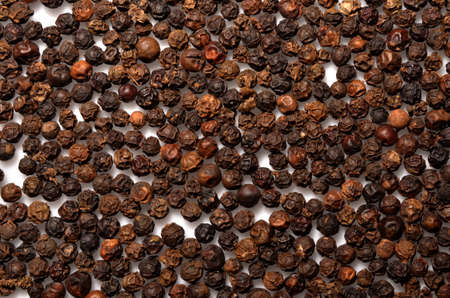 Dried black pepper grains texture, a close up photo of dry black pepper grains group on white...