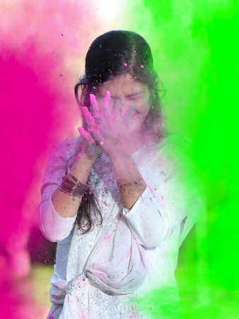 Portrait of happy Indian girl celebrating Holi with powder colours or gulal. Concept of Indian...