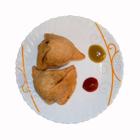 Indian evening snack, aloo samosa, served with chilli and tomato sauce, in a white ceramic trayの写真素材