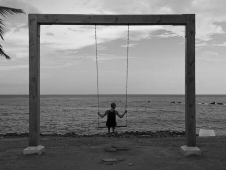 Shilhouette of woman on swing looking at the sea. Black and White - Image
