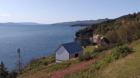 Canadian barn and fishing boat - are the castles of the country Canada. Ocean View.- Impressive, magnificent, irreplaceable. Haut Gaslesie. Quebec.- Old wooden barn in the countrysideの写真素材
