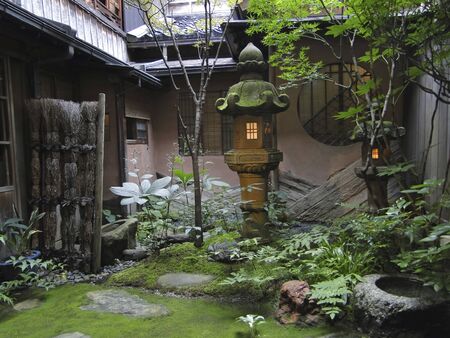 Japanese garden lamp Inner courtyard of a Japanese tea house. Traditional roofs Variety of plants and flowers.の写真素材