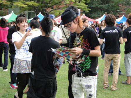 Kanazawa, Japan; September 10, 2010: University party in a park. Close-up of young Japanese with hat. Smile while browsing a magazineのeditorial素材