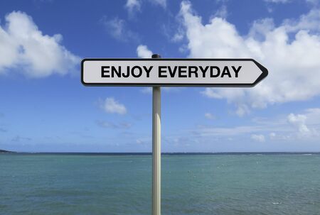 Road sign with ENJOY EVERYDAY text under caribbean sea background
