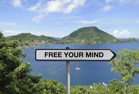 Road sign with FREE YOUR MIND text under tropical island backgroundの写真素材