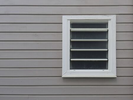 Close-up of white window on facade of horizontal sheets of painted wood. Tropical architecture. Martinique, French West Indiesの写真素材