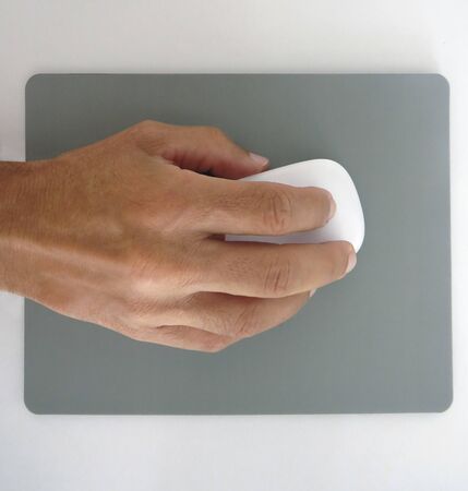 man's hand holding a white computer mouse and gray mouse padの写真素材