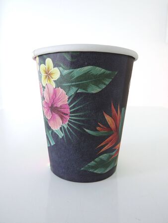 Isolated black takeaway disposable cup painted with Caribbean flowers on white background.の写真素材