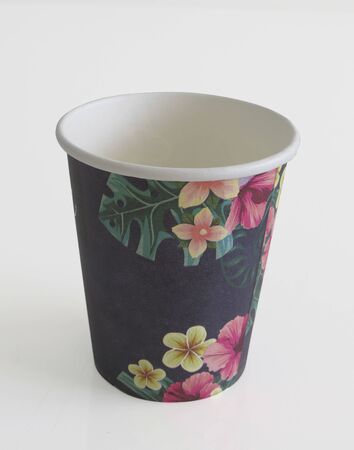 Isolated black takeaway disposable cup painted with Caribbean flowers on white background.の写真素材