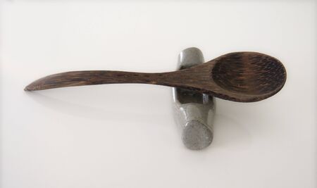 Spoon of dark wood on support for chopsticks isolated on white background. Grey cutlery support.の写真素材