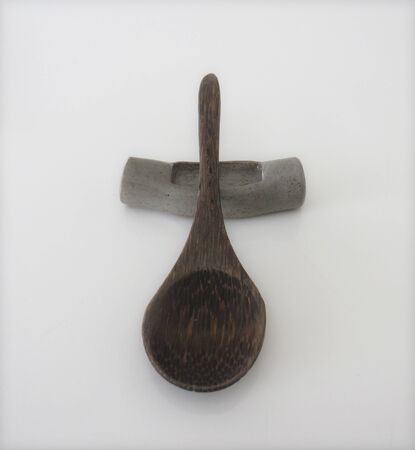 Spoon of dark wood on support for chopsticks isolated on white background. Gray cutlery support.の写真素材