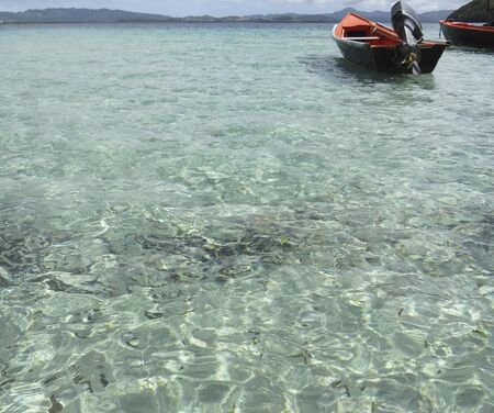 Transparent and turquoise waters of the Caribbean Sea with motorboat moored. Tropical sky. Idyllic Caribbean landscapeの写真素材