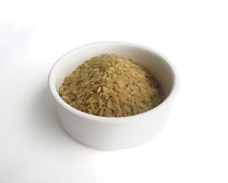 Organic raw Brown Rice in a white bowl on white background, angle view. Integral Wholegrain.の写真素材