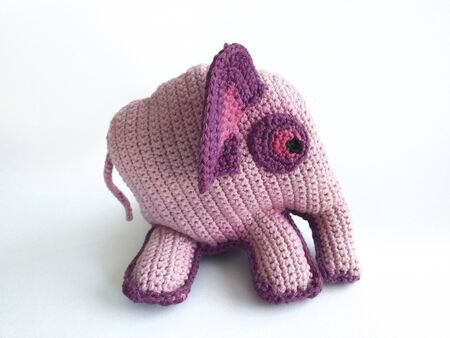 Close up of crochet animal. Lovely pink and purple elephant crochet knitted side view on white background.の写真素材