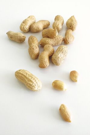 Frontal view of group of peanuts in shell and peeled on white background. Organic dried fruits for a...