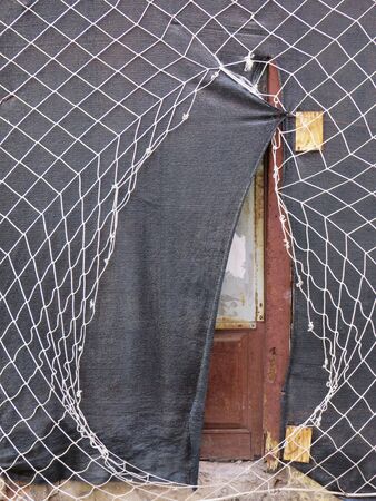 Rhombus-shaped wire mesh, gray canvas covering old door in rehabilitation. Construction Pattern.の写真素材