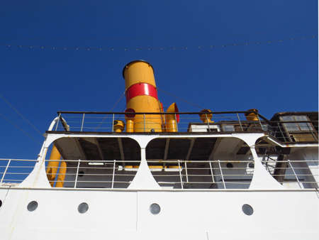 Close-up of Original Funnel or Yellow and Red Merchant Ship Chimney, under intense blue sky. Side view of deck and chimney of ferryの写真素材