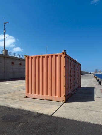 Side view of shipping container in industrial dock, and blue sky. Rectangular container for the...