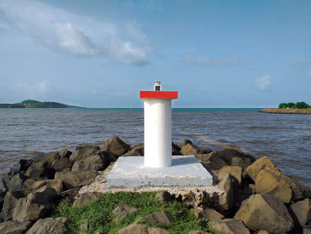 Port entrance signaling light. Entrance through Bocana with red port side marking light. Maritime and night navigation signals. Maritime beacon system.の写真素材