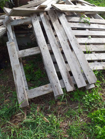 discarded wooden pallets abandoned. Stack of wooden boards background. Pile of grunge wood pallets placed randomly, dumped in outdoor area. Old scrapped wooden shipping pallets in a jumbled pile.の写真素材