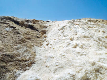 Background of pile of natural salt collected in saline on volcanic rock under blue sky. Ecosystem in...