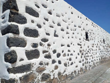 Perspective view of typical Canarian style white wall. Detail of traditional architecture and construction. White rural facade and black volcanic stone.の写真素材