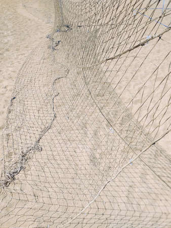 Fall beach volleyball net background. Beach sport net on white sand pattern. Lack of maintenance of...