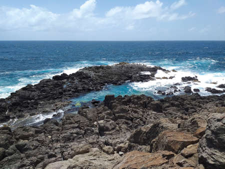 Rocky Caribbean coastline with turquoise whitewater under tropical blue sky. Rocks carved by the tropical waters of FWI. Magical environment of wild nature background.の写真素材
