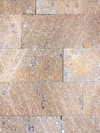 Ocher stone wall abstract background. Colored wall of rectangular stones. Beige bricks in masonry...