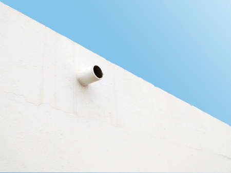 Perspective view of round drain pipe in white concrete exterior wall. Tropical Construction and...