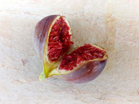 Close up of cut and open fresh ripe fig. Fruit of the purple-skinned fig tree with reddish pulp and...