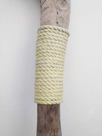 Thick braided rope tied on wooden stick on white background. Skein of rope jute. Rustic rope roll....