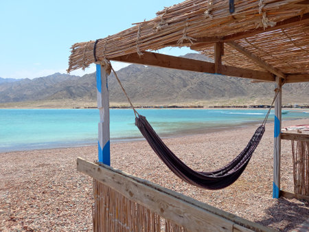 Hammock in rustic cabin on the Sinai coast. Desert and extreme landscapes. Turquoise waters with a hammock for relaxing on the beach.の写真素材