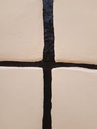White cement rough wall background with black wooden slats. Detail of beams, lumber and other...