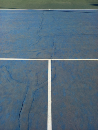 Close up of blue tennis court with white lines of service area. Old hard tennis court surface. Racquet sports and physical activity.の写真素材