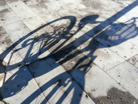 On the asphalt of the sidewalk, the shadow of a bike.Shadow on street tilesの写真素材