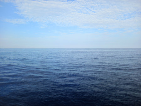 Panoramic view of a calm sea. Background of the horizon with ocean and a blue sky with white clouds. Maritime landscapes. Relaxation.の写真素材