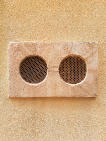 Round ventilation grills on exterior facade. Close-up of ventilation grills on stone and cement wall. Rustic smoke and air vents. Architecture and Construction.の写真素材