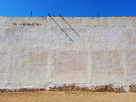 Front view of a white cement wall under a blue sky and a red brick floor. White stone wall. Architecture and Constructionの写真素材