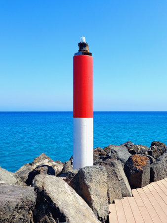Red and white maritime signal. Beacon towers and posts. Port and coastal beacons. Maritime signal beacon under a blue sky.の写真素材