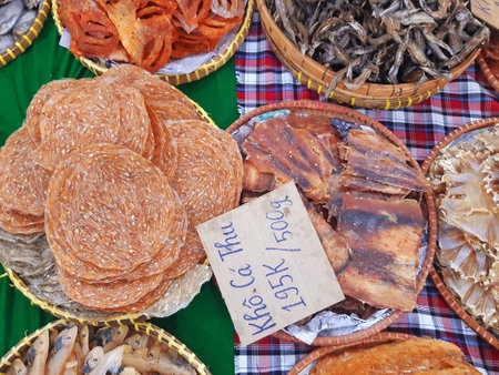 A variety of Vietnamese dried fish with a sign for "khÃ´ cÃ¡ thu" (dried mackerel) and a price tag. Asian food. Aerial view of salted fish for sale at the market.の写真素材