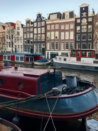 Close-up of houseboats moored in an Amsterdam canal. Panoramic view of Dutch facades and boats. Urban planning and culture of the Netherlands.の写真素材