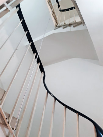 A winding geometric staircase with a black iron banister in a stately home stairwell. Stairs in a building in perspective.の写真素材